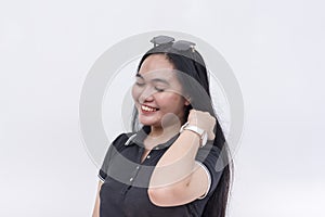 A young upbeat asian woman wearing a black polo shirt feeling blissful stroking her hair. Isolated on a white background