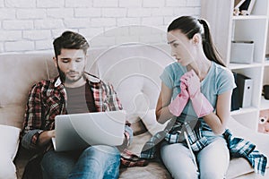 Young Upset Woman Cleaning Room with Lazy Man.