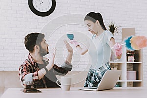 Young Upset Woman Cleaning Room with Lazy Man.