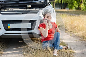 Young upset woman crying because of broken car calling auto service for help