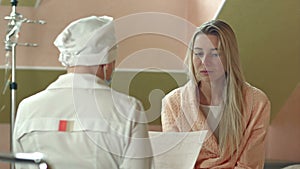 Young upset woman in hospital bed listening to doctor prognosis