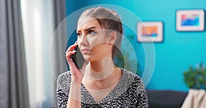 A young upset woman is talking to someone on the phone. Serious female having worried