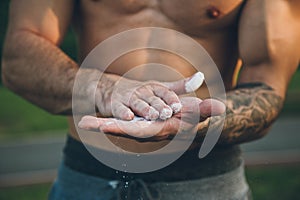 Young urban bodybuilder coating his hands with magnesium chalk for calisthenics training