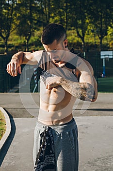 Young urban bodybuilder taking off the shirt before calisthenics training