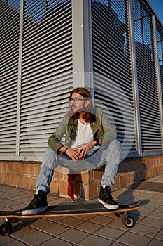 Young urban hipster guy wearing casual attire with skateboard