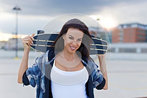 Young urban woman holding longboard behind head