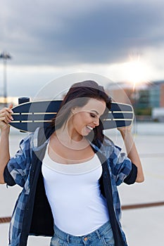 Young urban woman holding longboard behind head have fun