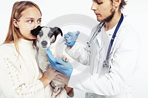 Young veterinarian doctor in blue gloves examine little cute dog jack russell isolated on white background with owner