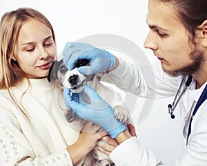 Young veterinarian doctor in blue gloves examine little cute dog jack russell isolated on white background with owner