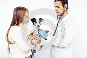 Young veterinarian doctor in blue gloves examine little cute dog jack russell isolated on white background with owner