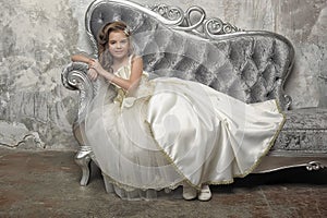 Young Victorian princess sitting on a silver sofa