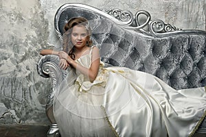 Young Victorian princess sitting on a silver sofa