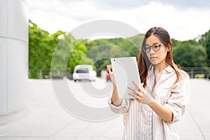 Young Vietnamese woman using tablet, connecting to electric car charge station