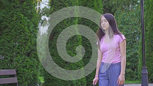 Young visually impaired asian woman with a cane is in the park slow mo