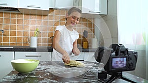 Young vlogger recording video content for food blog kneading dough