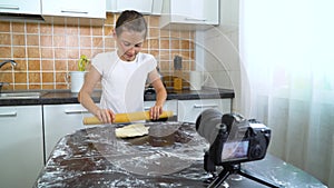 Young vlogger recording video content for food blog rolling dough with rolling pin