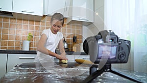 Young vlogger recording video content for food blog rolling dough with rolling pin