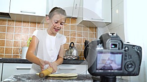 Young vlogger recording video content for food blog rolling dough with rolling pin