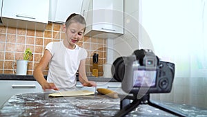 Young vlogger recording video content for food blog rolling dough with rolling pin