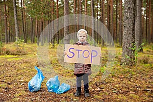 Young volunteer child cleaning forest environment from rubbish pollution