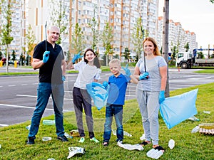 A young volunteer family collects plastic bottles and other rubbish. Garbage cleanup. Ecological volunteer concept.