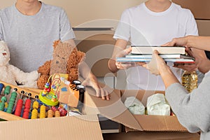 Young volunteers collect donations for charity indoors. Donation boxes with clothes, food, toys, school supplies