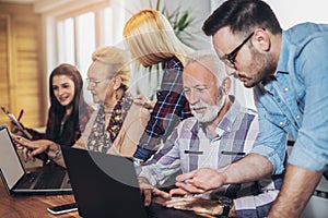 Young volunteers help senior people on the computer.