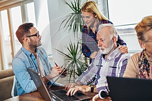 Young volunteers help senior people on the computer