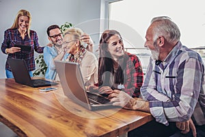 Young volunteers help senior people on the computer.
