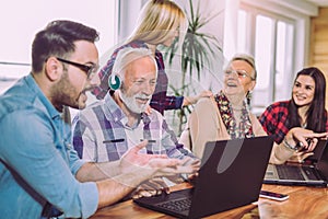 Young volunteers help senior people on the computer.