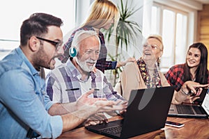 Young volunteers help senior people on the computer.