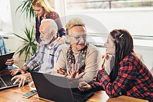 Young volunteers help senior people on the computer.