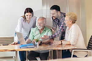 Young volunteers help senior people on the computer.