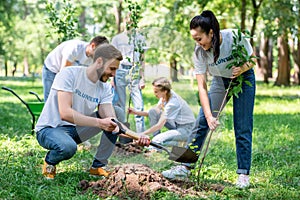 young volunteers planting trees in green