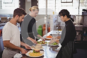 Young wait staff with fresh food in plates on kitchen counter