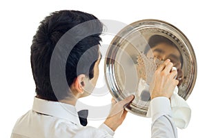 The young waiter with black hair waxes to shine tray for cupboards close-up