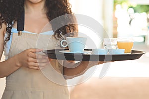 Young waiter holding tray