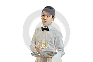 The young waiter looks away and takes the ball tray with a glass of champagne