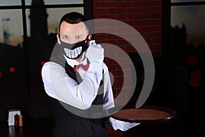 A young waiter removes a funny animated mask from his face.Preventing the spread of the virus. The threat of coronavirus