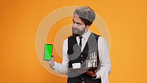 Young waiter shows greenscreen on camera