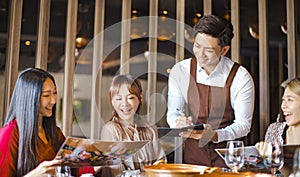 Young waiter  taking an order  in hot pot reataurant