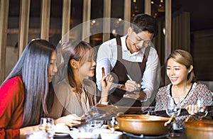 Young waiter  taking an order  in hot pot reataurant