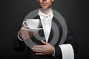 Young waiter in uniform serving hot coffee