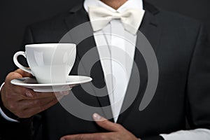 Young waiter in uniform serving hot coffee