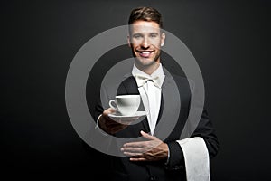 Young waiter in uniform serving hot coffee