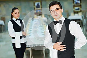 Young waiter and waitress at service in restaurant