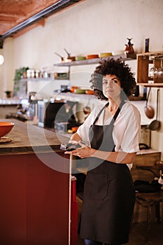 Young waitress working with the card terminal behind the bar counter of a restaurant