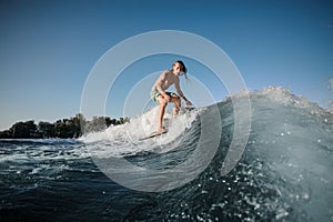Young wakesurfer conquers a high wave on a board photo