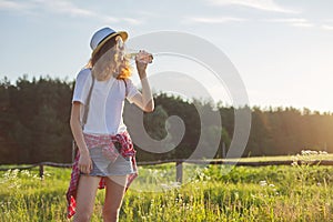 Young walking teen girl drinking water from bottle