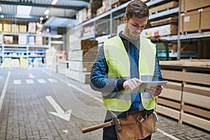 Young warehouse worker consulting a tablet